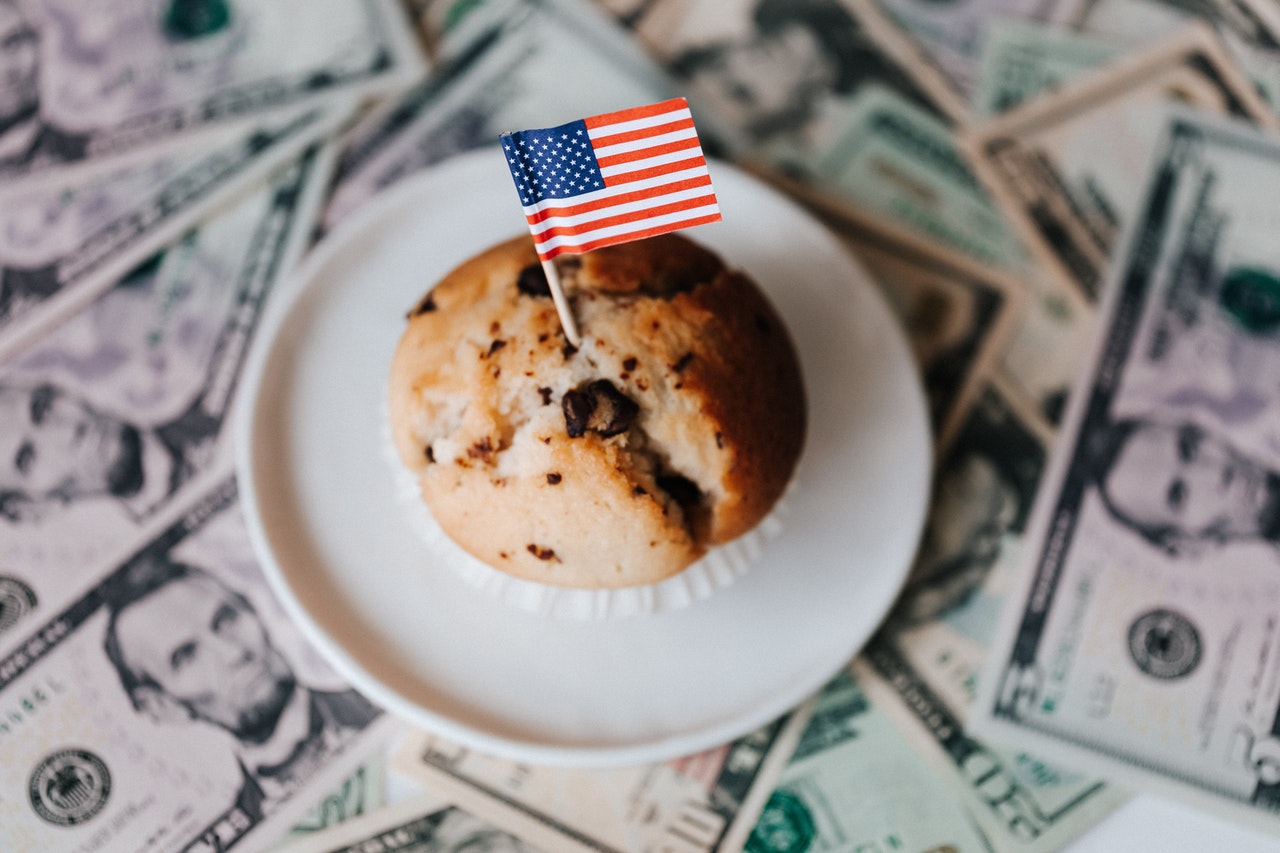 Tasty cake with flag on bunch of paper dollars